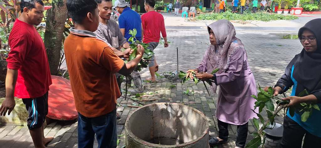 OLAH SAMPAH: Guru SDN 19 Cakranegara membuang daun perampingan pohon ke lubang untuk diolah menjadi pupuk kompos di sekolah setempat, Sabtu (4/1).