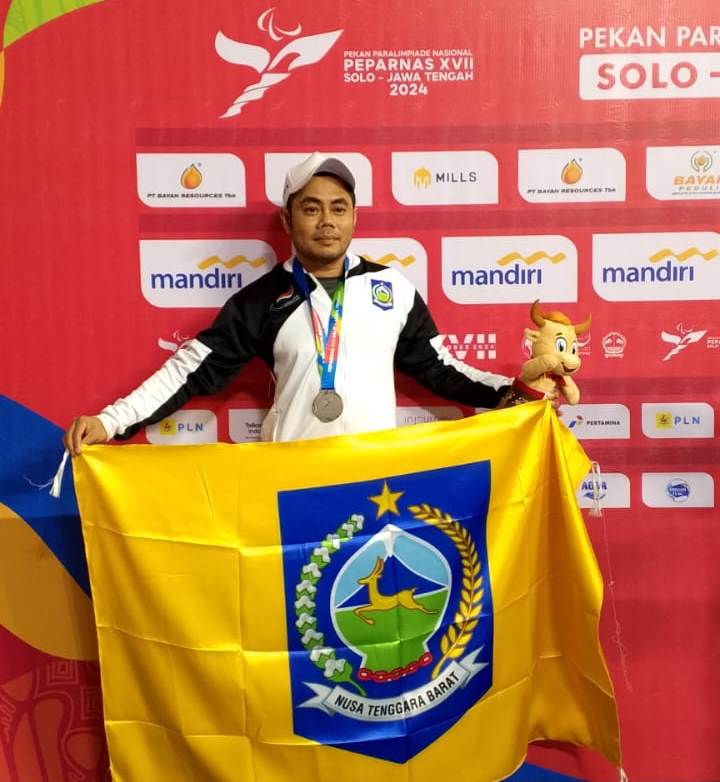 HARUMKAN DAERAH: Syamsul Khair membentangkan bendera pataka NTB saat meraih medali perak di Pekan Paralimpiade Nasional (Peparnas) XVII Solo, Jawa Tengah 2024 lalu.