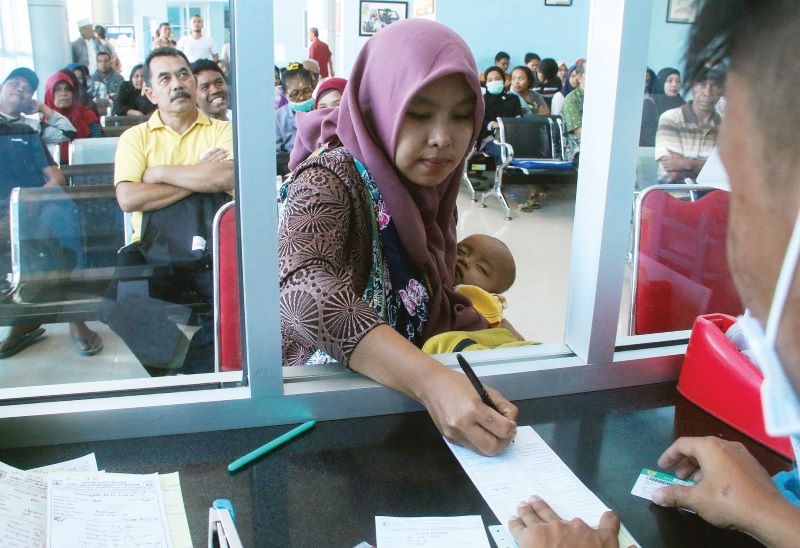 MELAYANI: Seorang pasien sedang melakukan transaski pembayaran di loket RS Kota Mataram beberapa waktu lalu. (Ivan/Lombok Post)
