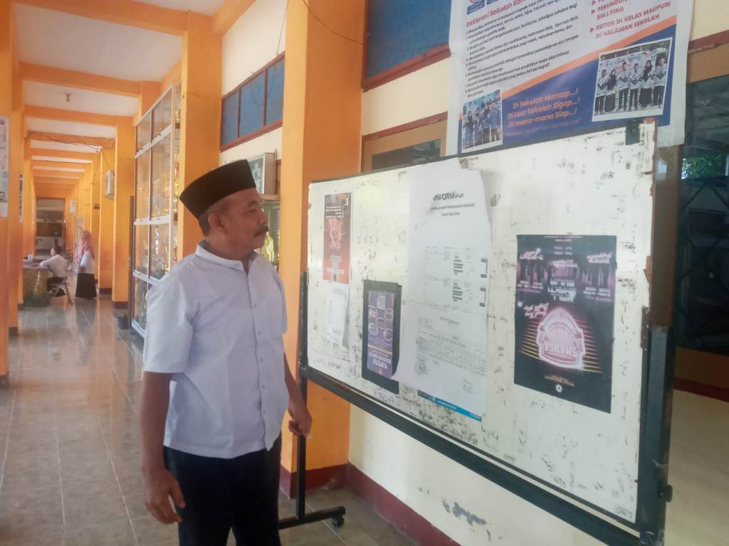TRANSPARAN: Kepala SMPN 13 Mataram H Ahmad Saehu memperhatikan penggunaan dana BOS di papan informasi sekolah setempat, Rabu (15/1).