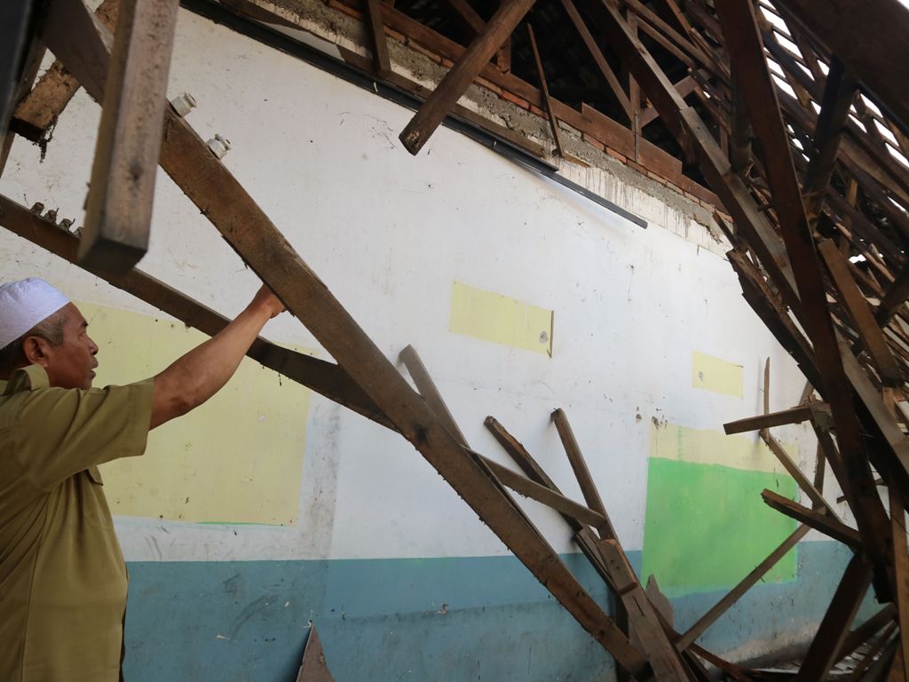 TERMAKAN USIA: Kepala SMP Negeri 2 Jonggat Mahyun menunjukkan kondisi atap ruang kelas yang ambruk akibat angin kencang Minggu, (2/2) lalu.