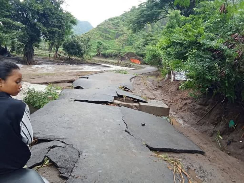 JALAN RUSAK: Seorang warga tidak bisa melintas karena jalan dan jembatan putus diterjang banjir di Kecamatan Wera, Bima, Senin (3/2).