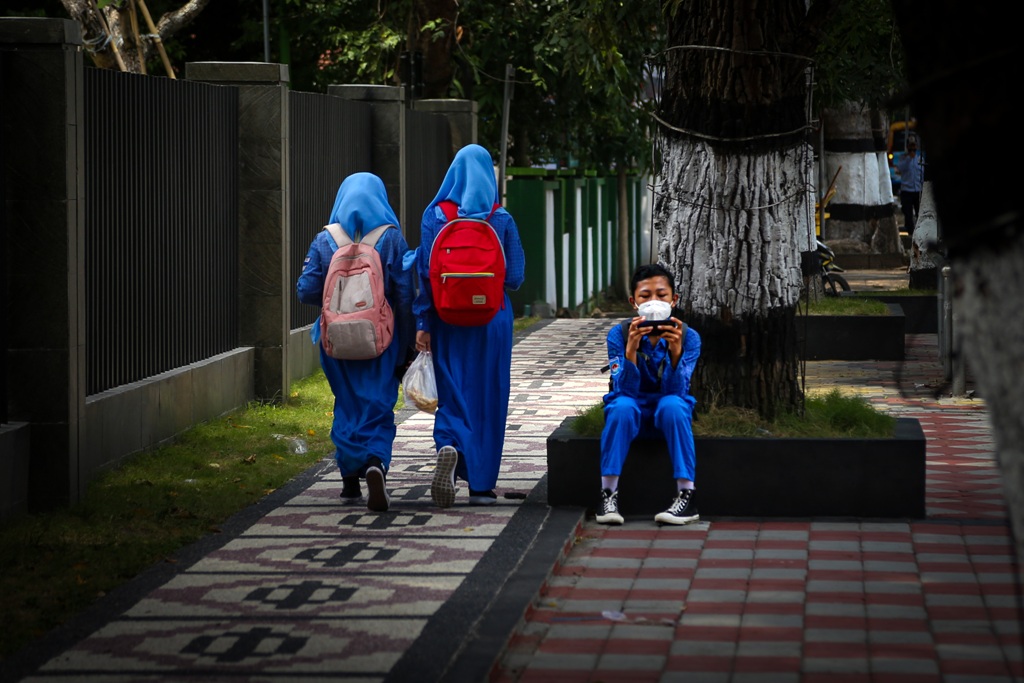 MULAI DIBATASI: Seorang siswa tengah asyik bermain smartphone di lingkungan sekolahnya.