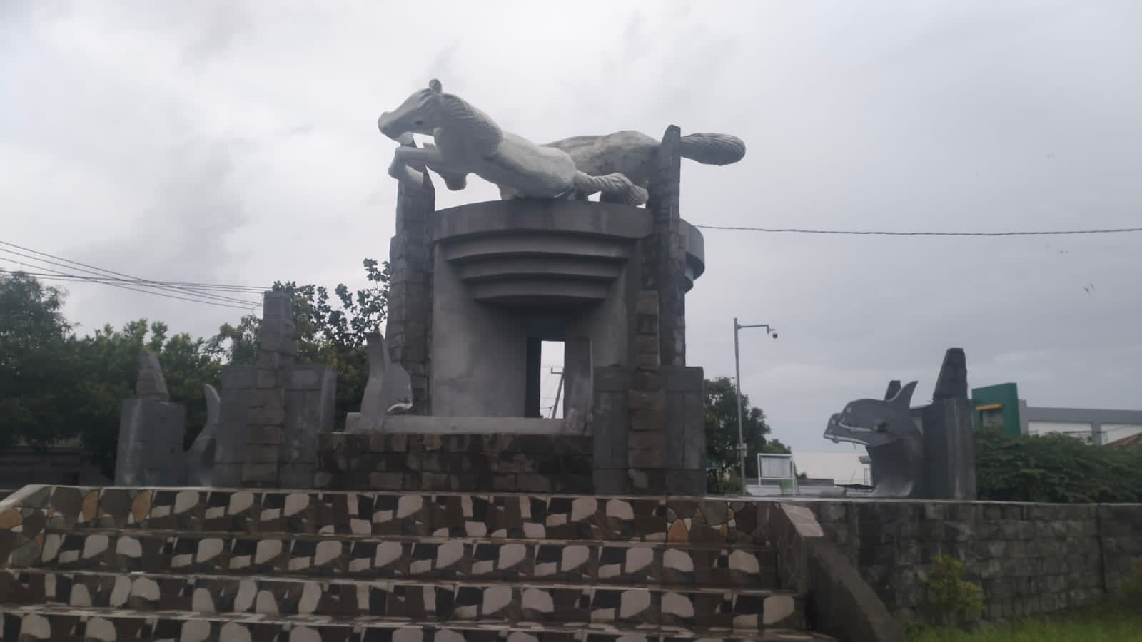 Kondisi patung kuda di bundaran rest area Kayangan yang roboh karena hujan lebat dan angin kencang.