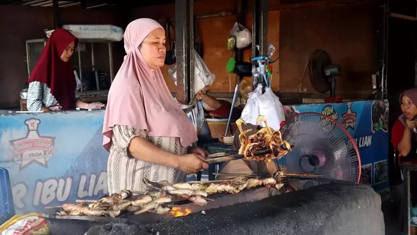 BAKAR PESANAN PELANGGAN: Lian yang tengah membakar ayam kampung pesanan pelanggan di depan warungnya, belum lama ini.