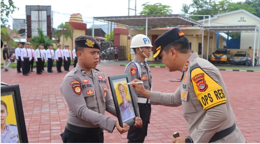 DIPECAT: Kapolres Sumbawa AKBP Bagus Nyoman Gede Junaedi mencoret foto anggota yang dipecat dalam upacara PTDH di Lapangan Wicaksana Laghawa, polres setempat, Selasa (11/2).
