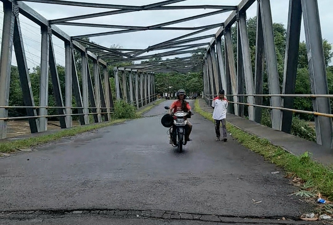 NEKAT: Salah satu pengendara motor melintas di Jembatan Bakong, Lombok Barat yang nyaris roboh akibat diterjang air sungai yang meluap.