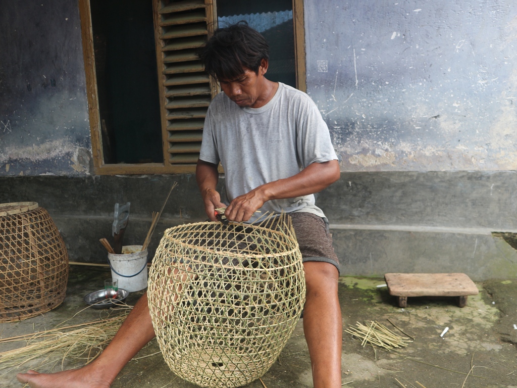 BUAT ANYAMAN: Lalu Suhirman, perajin kurungan burung merpati membuat kurungan di teras rumahnya, di Dusun Repok Payung, Desa Rarang, Kecamatan Terara, Kabupaten Lombok Timur.
