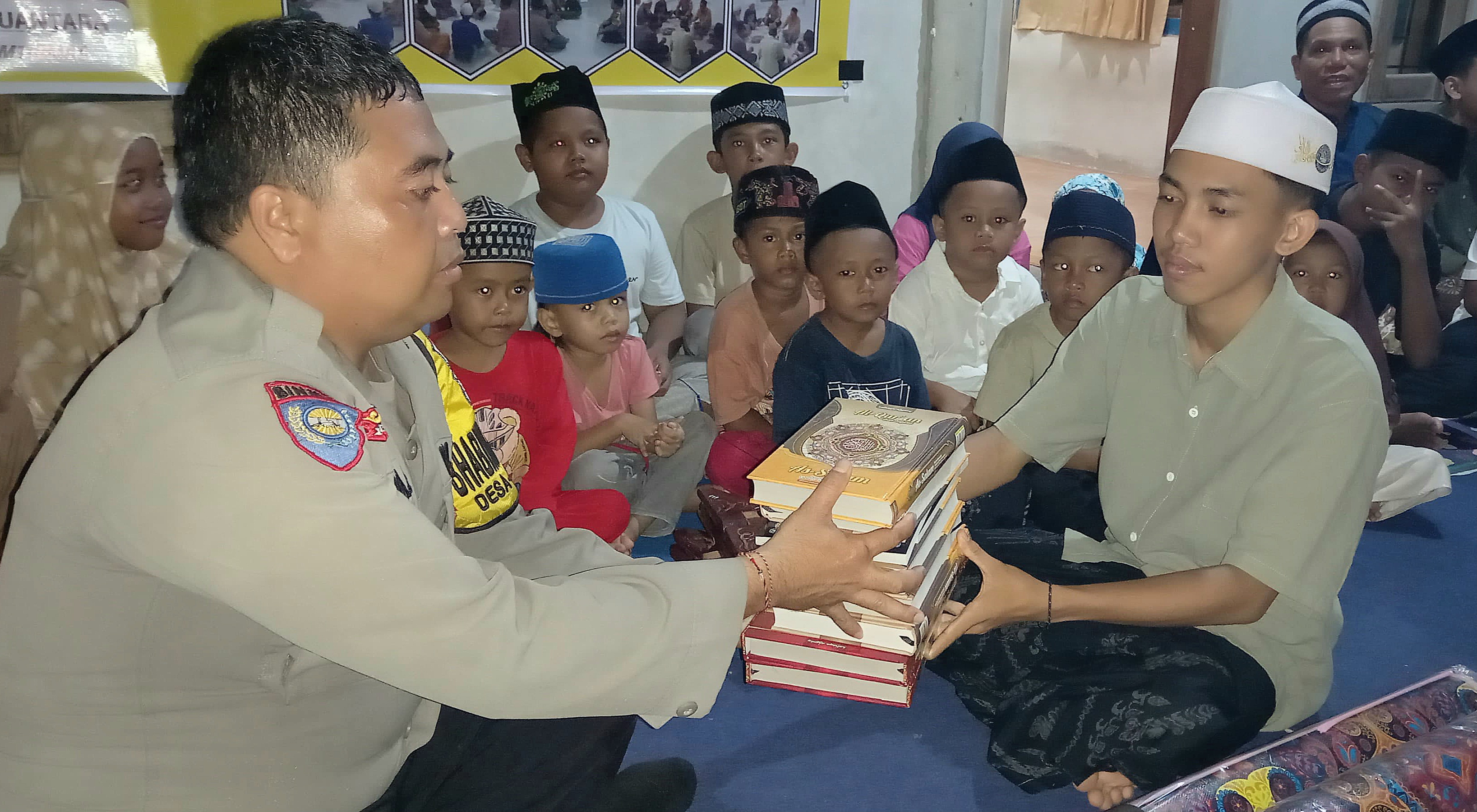 POLISI TELADAN: Aipda Gede Arya Suantara, Bhabinkamtibmas Desa Gontoran saat menyalurkan bantuan ke TPQ Al-Kasim, Sabtu (22/2).