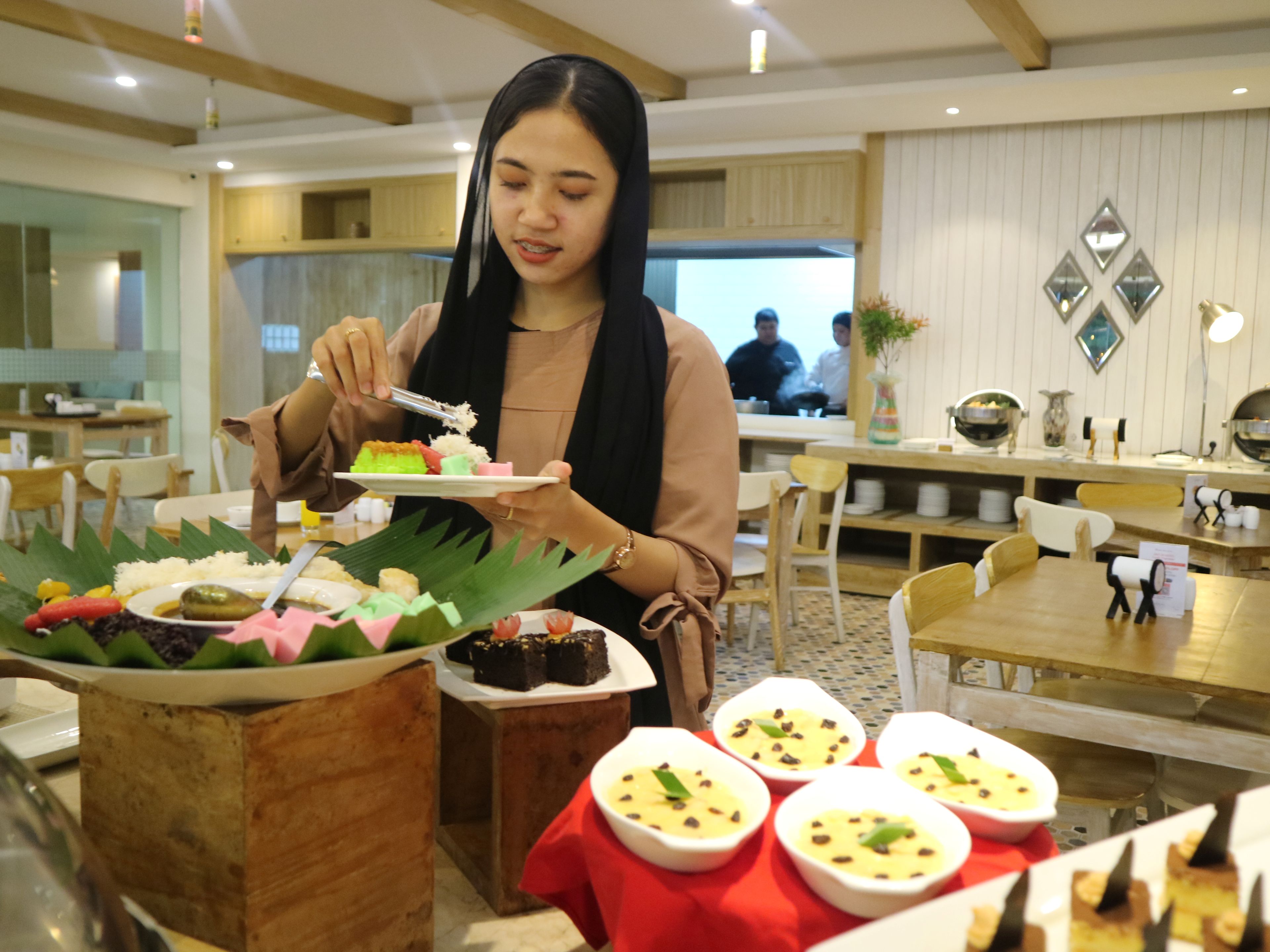 Seorang pegunjung mencicipi aneka hidangan yang disajikan dalam program All You Can Eat Ramadan Iftar di Swiss-Bistro, Hotel Swiss-Belcourt Lombok, Loteng, Selasa (25/2).