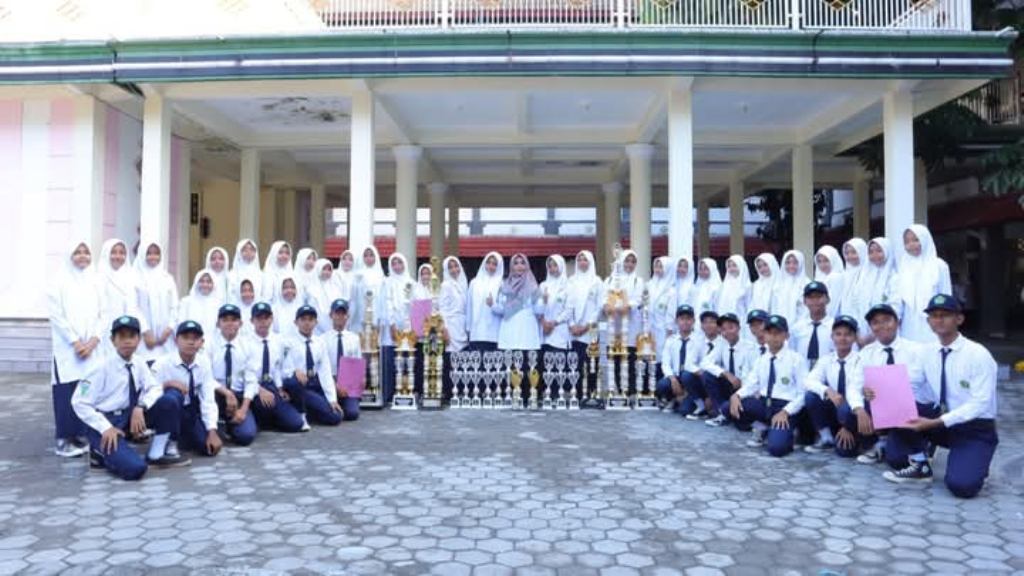 BERPRESTASI: Kepala MTsN 1 Mataram Hj Rusniah bersama siswa yang meraih medali ajang ISO NTB di halaman madrasah setempat, Minggu (2/3).