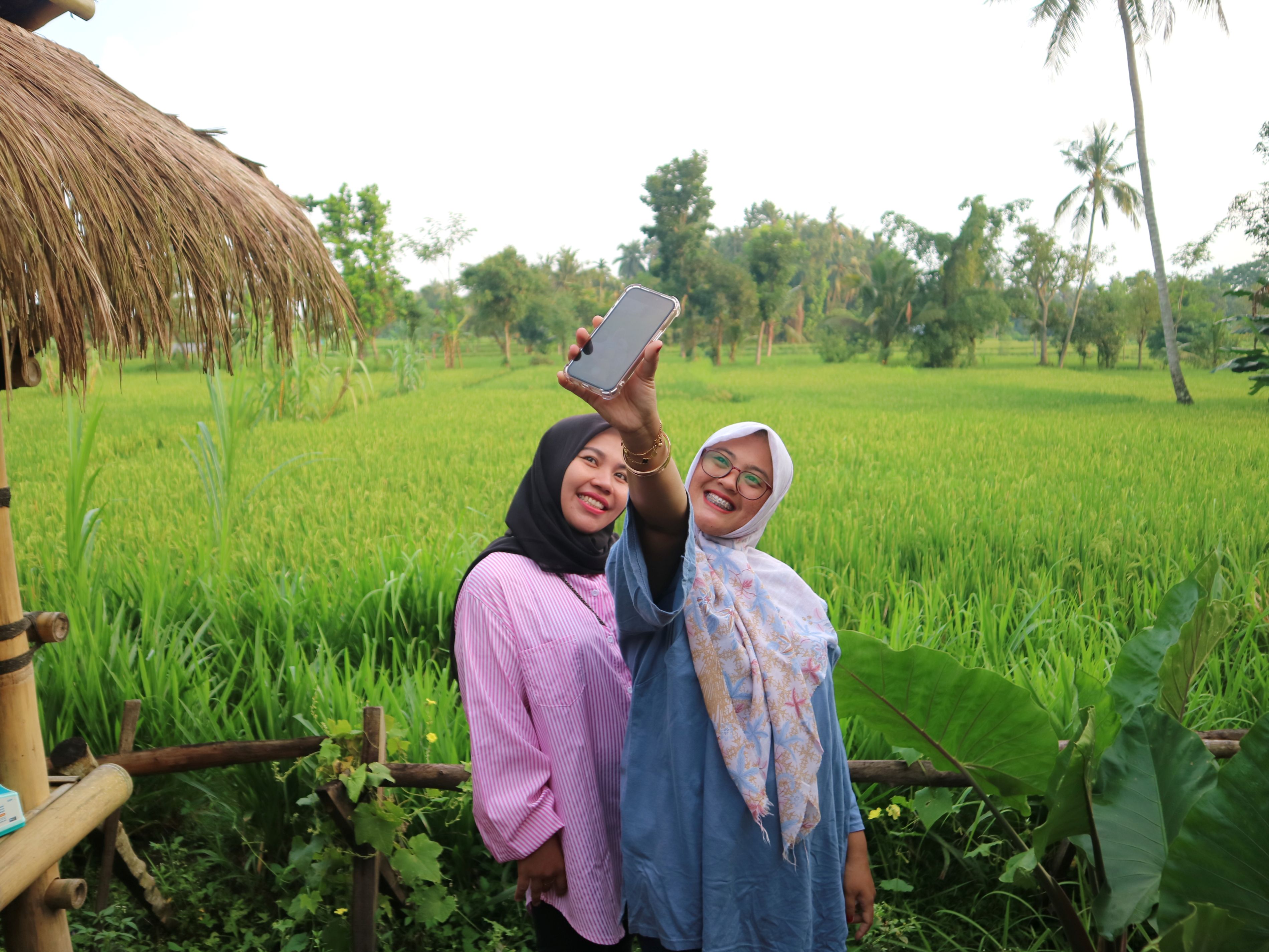 TEMPAT FAVORIT: Pengunjung asyik berswafoto dengan latar persawahan sembari menunggu waktu berbuka puasa di Warung Bambu 2 Bonjeruk, Desa Bonjeruk, Kecamatan Jonggat, Loteng, Selasa