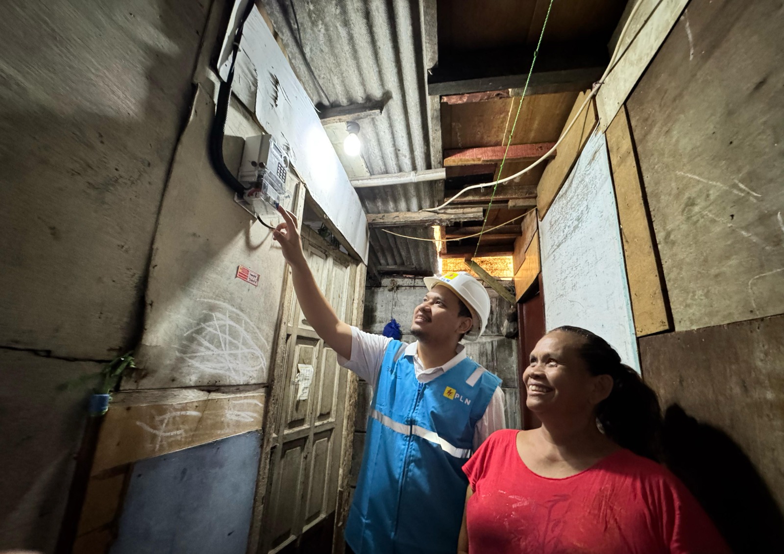 Umi (kanan), salah satu warga Kelurahan Menteng Atas, Kecamatan Setia Budi, Jakarta Selatan, tampak bahagia dengan kehadiran listrik yang disambung oleh petugas PLN.