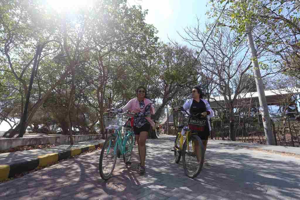DESTINASI UNGGULAN: Dua wisatawan lokal yang berlibur sedang menikmati keindahan alam, dengan berkeliling menggunakan sepeda di kawasan Gili Trawangan.