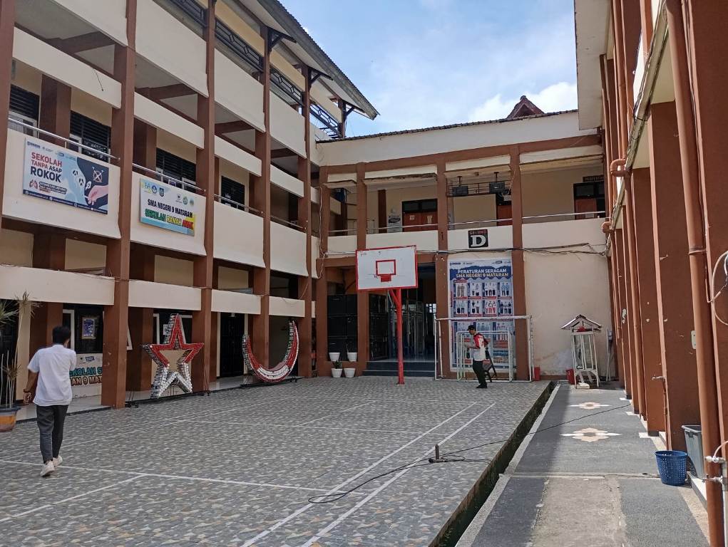 MINIM LOLOS: Seorang guru SMAN 9 Mataram berjalan di halaman sekolah, belum lama ini.