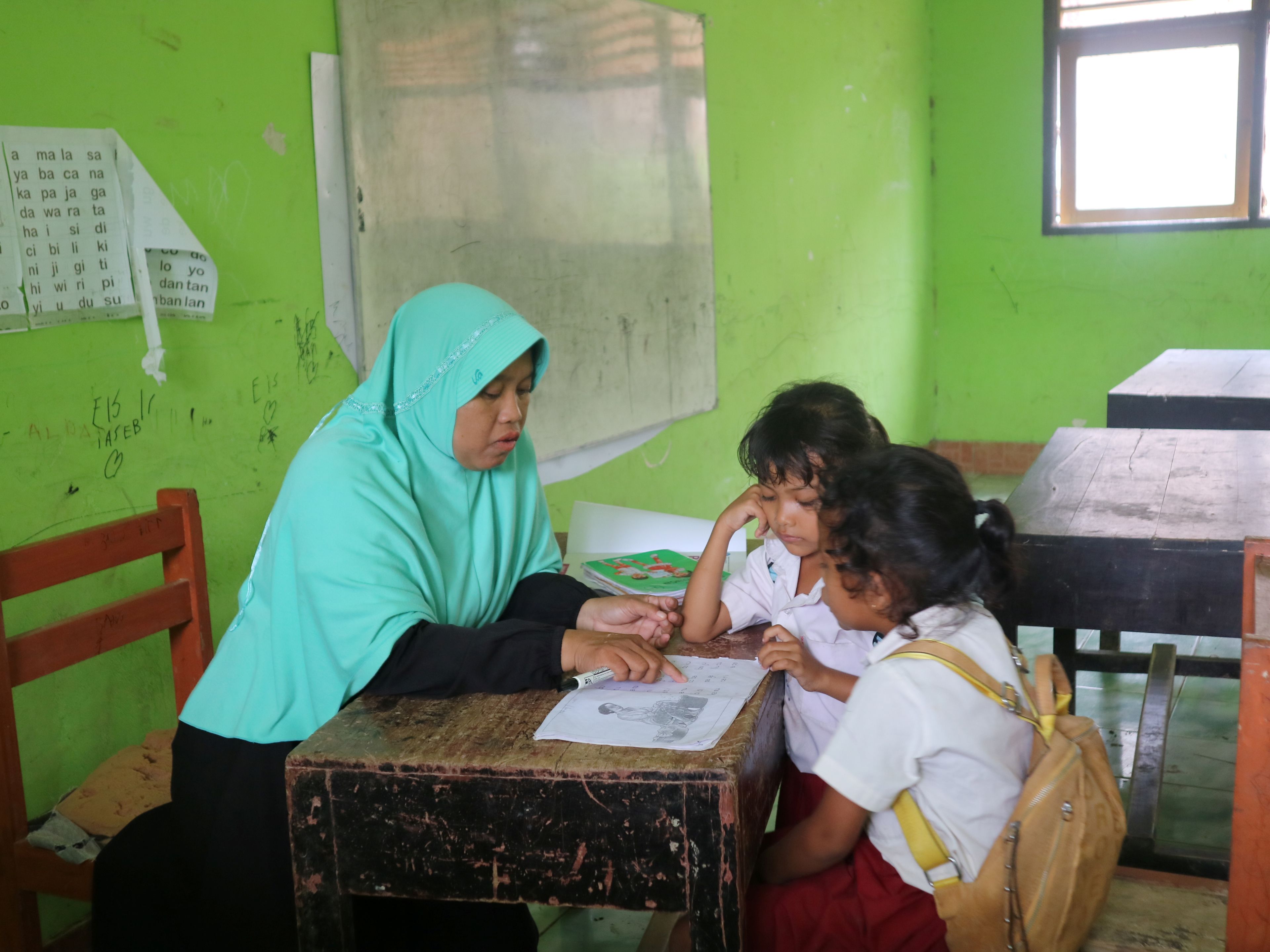 Seorang guru sedang mengajar membaca sejumlah muridnya di Lombok Tengah.