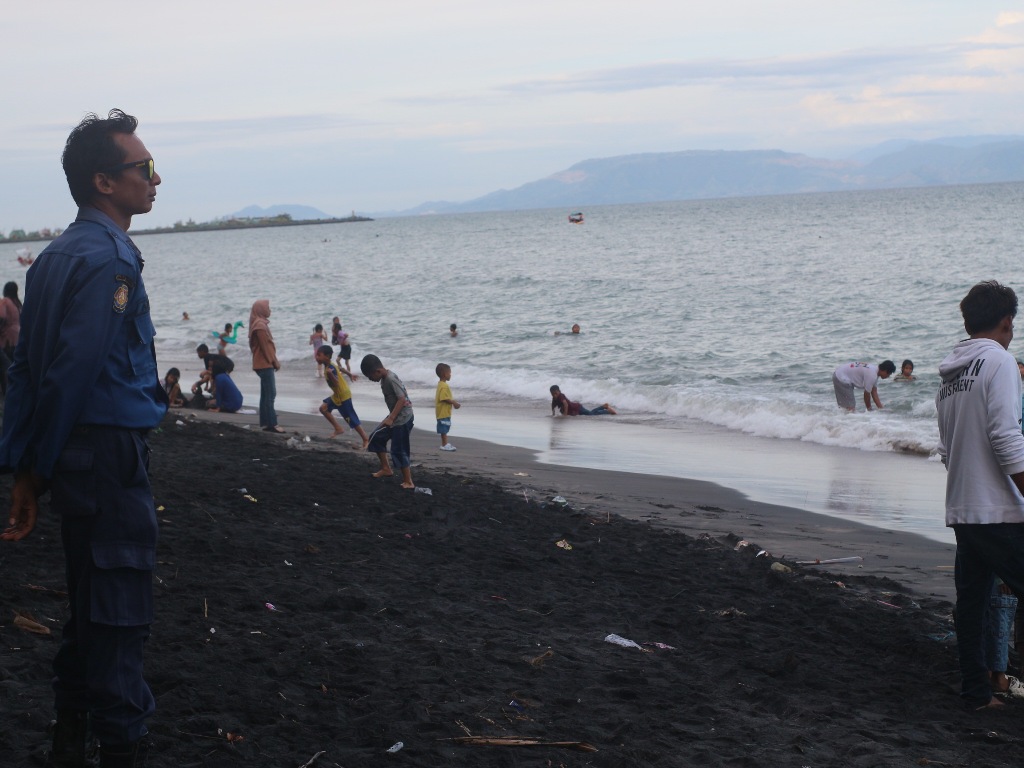 JAGA KEADAAN: Petugas Damkarmat Lombok Timur (Lotim) memantau aktivitas masyarakat yang sedang mandi di pantai Sunrise Land Lombok (SLL), Senin (7/4).