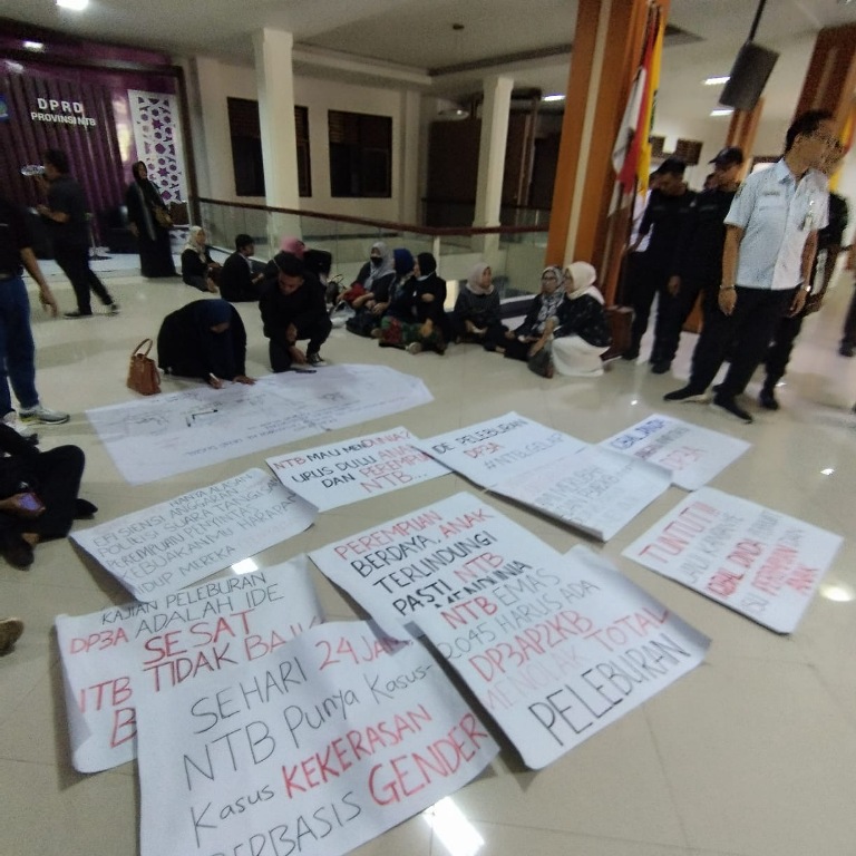 PENOLAKAN: Aliansi pemerhati perempuan dan anak NTB membawa poster bertuliskan penolakan penggabungan Dinas Pemberdayaan Perempuan, Perlindungan Anak, Pengendalian Penduduk, dan Keluarga Berencana.