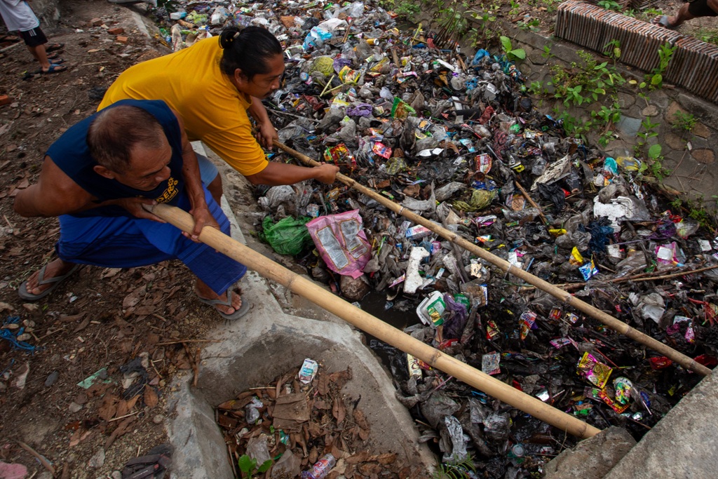 BIANG MASALAH: Masyarakat tengah membersihkan lingkungan dari sampah yang menutupi saluran, beberapa waktu lalu.