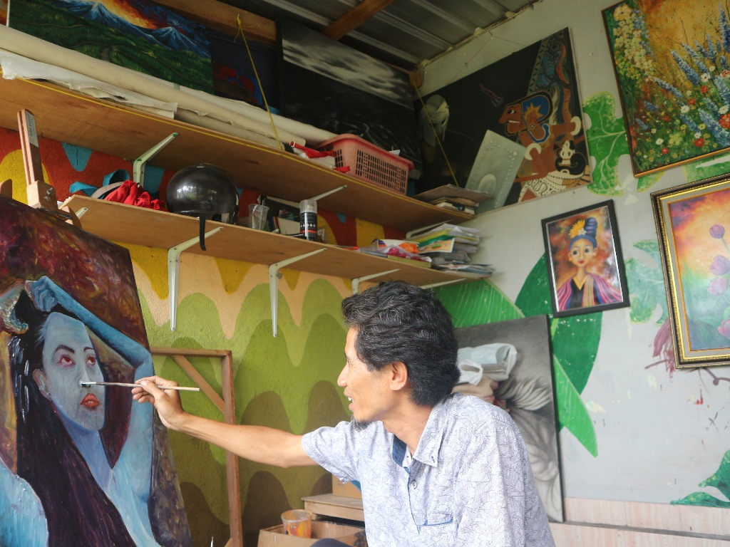 FOKUS: M Zulfiandi saat melukis seorang perempuan di sanggar Naluri miliknya, di Desa Aikmel Barat, Kecamatan Aikmel, Minggu (20/4).