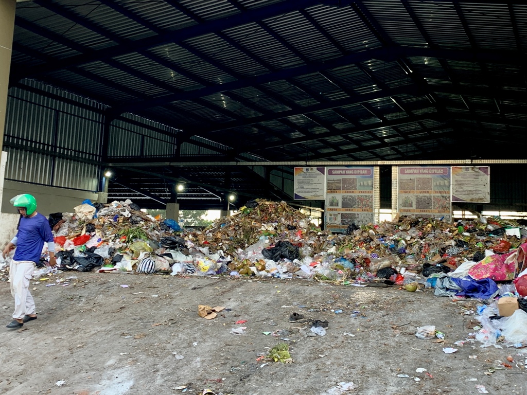 Seorang warga membuang sampah di TPST Sandubaya. Telihat tumpukan sampah yang mulai meninggi, pekan ini.&nbsp;