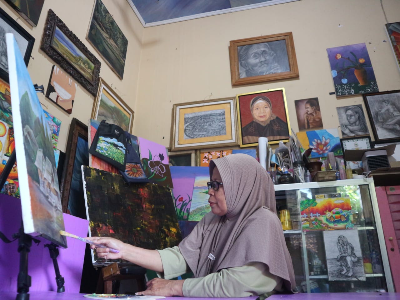 MELUKIS: Maimanah saat melukis di sanggar seni lukis Arus ide miliknya di Lingkungan Seruni, Kelurahan Selong&nbsp; Kecamatan Selong. Minggu (27/4).