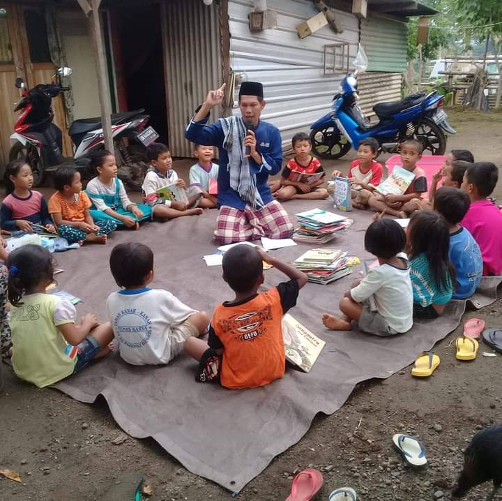 PEGIAT LITERASI: Assudin bersama anak-anak di Kecamatan Bayan saat membawakan buku untuk anak-anak tersebut.