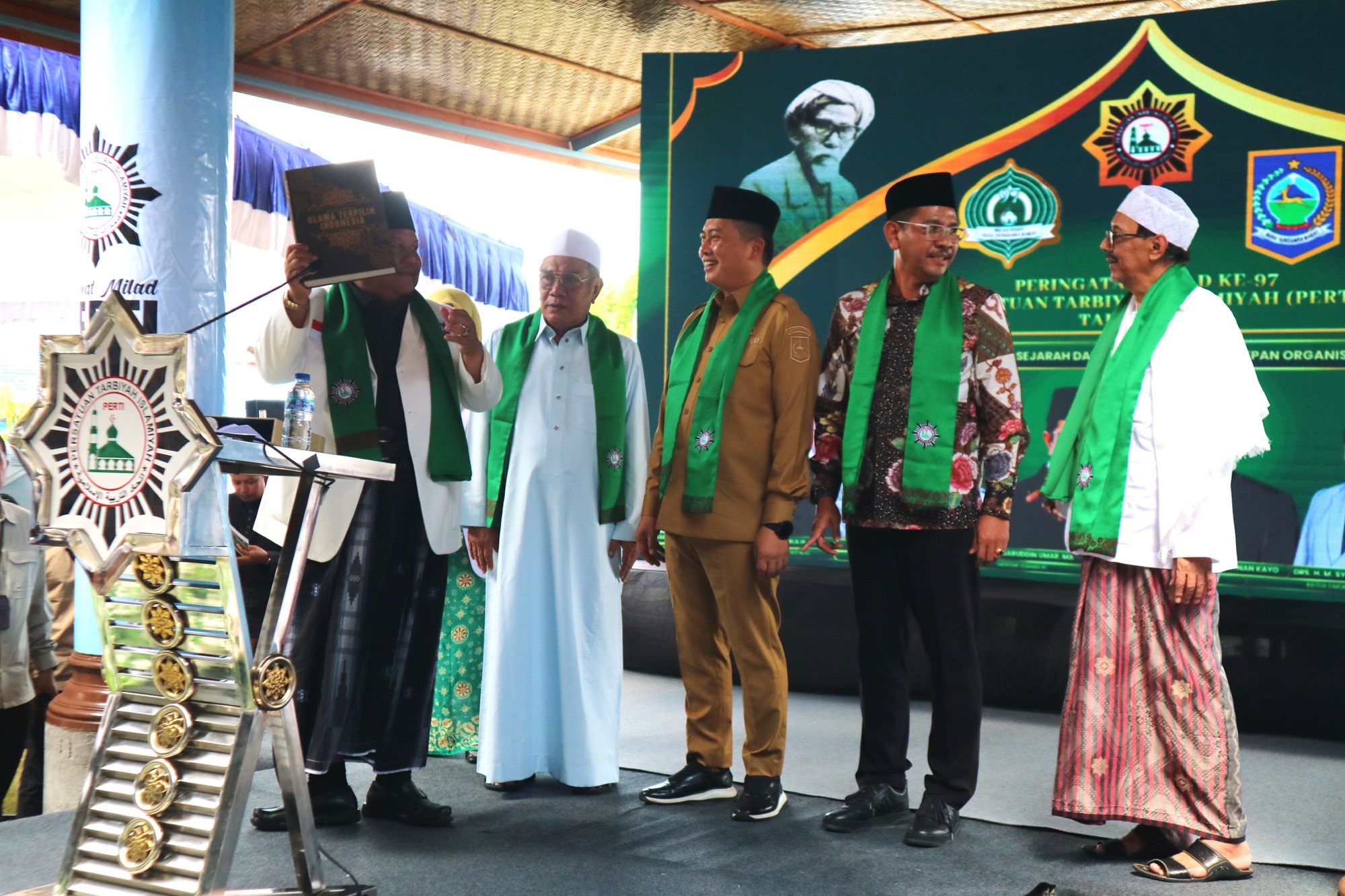 MILAD PERTI: Ketua Umum Perti H Syarfi Hutauruk (kiri) menyerahkan buku Ensiklopedia Ulama Terpilih Indonesia kepada Gubernur NTB Lalu Muhamad Iqbal, Pengurus Yatofa Bodak TGH Achmad Fadli FT