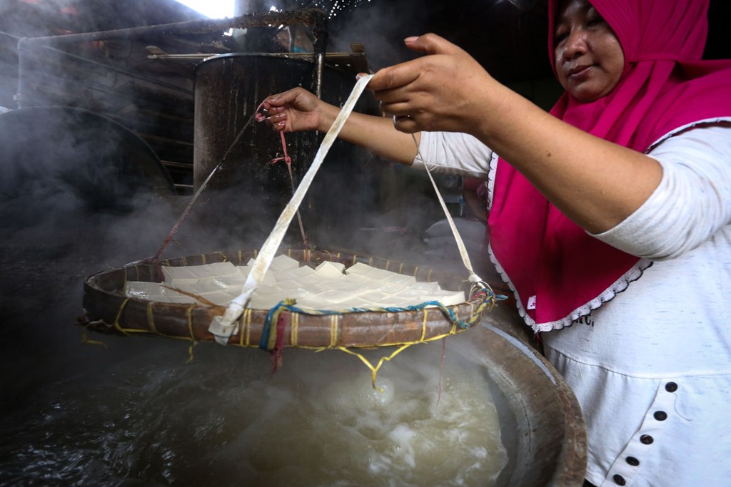 WIRAUSAHA BARU: Seorang pembuat tahu di Kota Mataram saat melakukan penyaringan, beberapa waktu lalu.&nbsp;