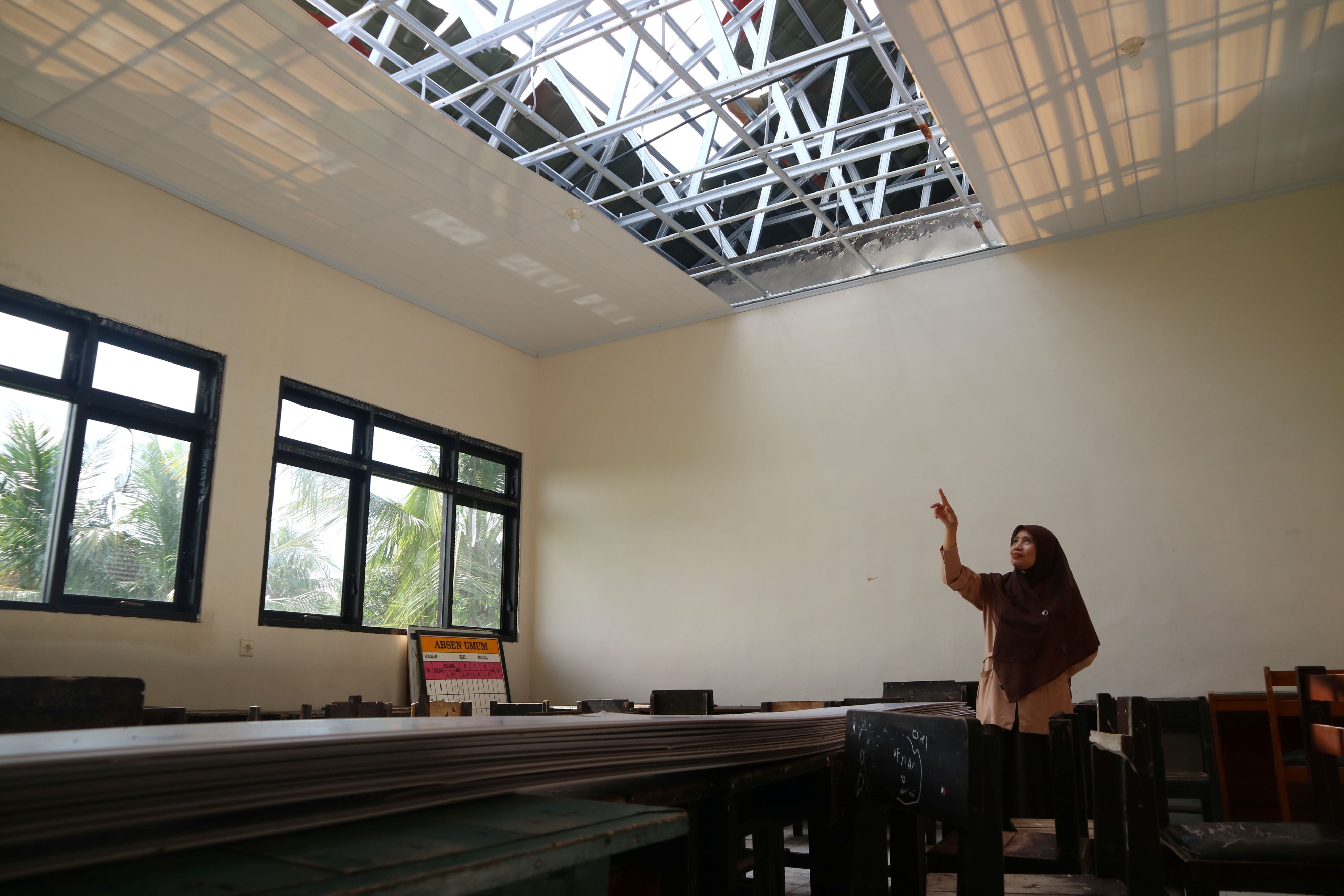 Kepala SDN Wakan Sri Wahidah menunjukkan salah satu kondisi atap dan plafon ruang perpustakaan usai diterjang angin puting beliung, di Dusun Waker, Desa Puyung, Kecamatan Jonggat, Loteng, Rabu (14/5).