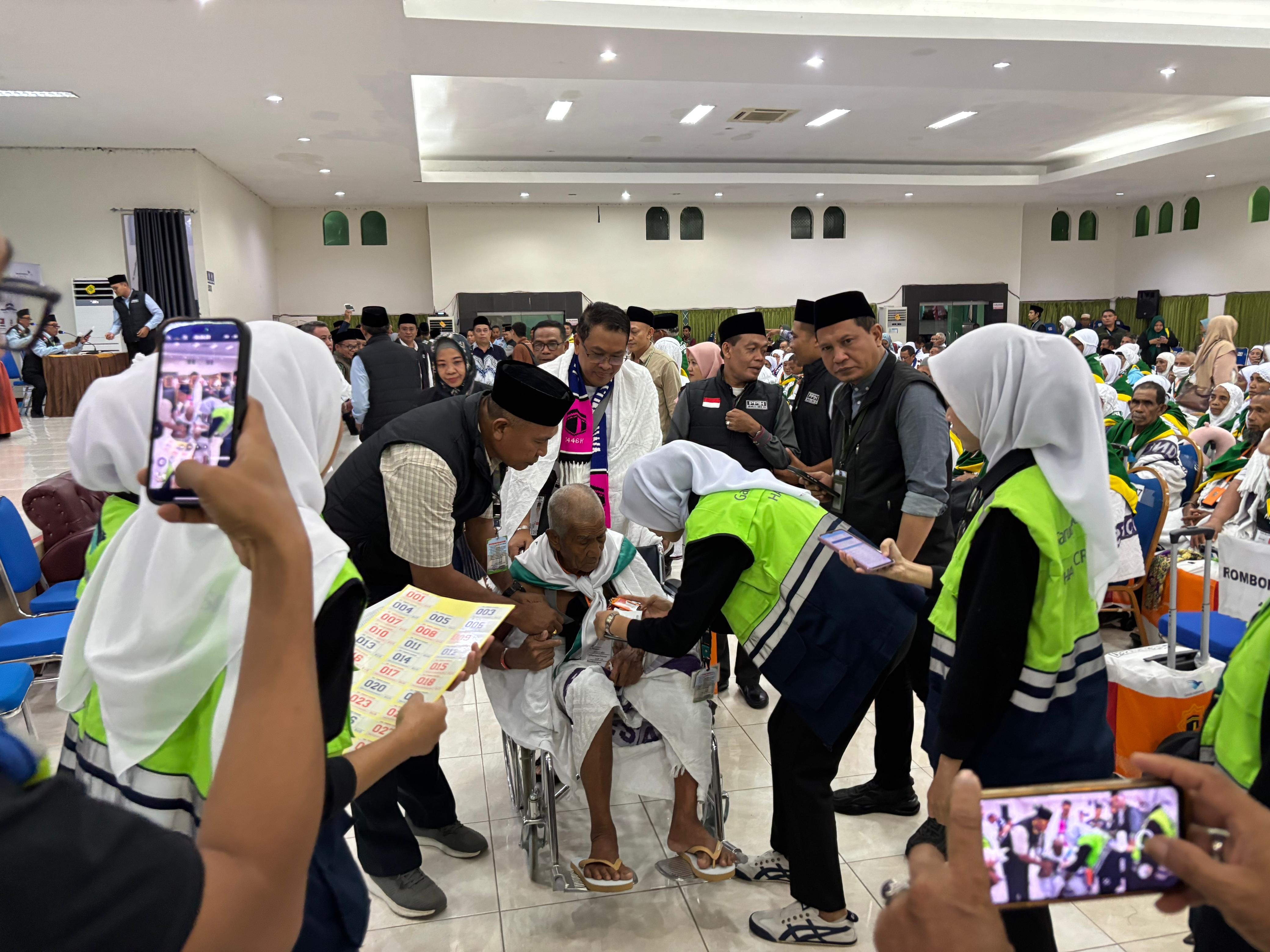 Seorang JCH dari Kloter 12 yang termasuk jamaah prioritas lansia, dibantu petugas menyiapkan dokumen keberangkatan, saat pelepasan di aula BIR ALI 1 UPT Asrama Haji Embarkasi Lombok, Jumat (16/5)