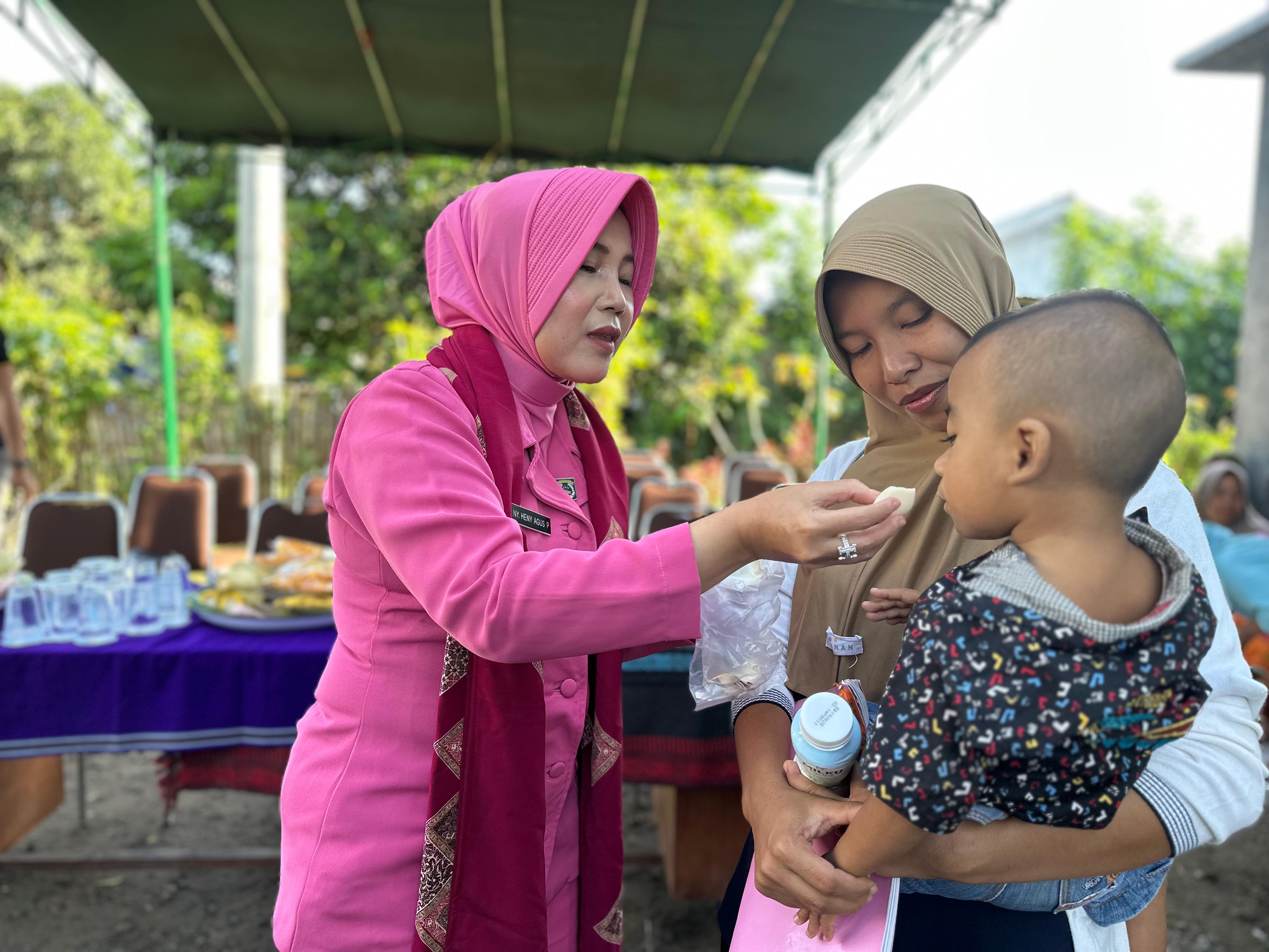 Ketua Byangkari Cabang Lombok Utara Heny Agus Purwanta menyuapkan telur kepada seorang anak