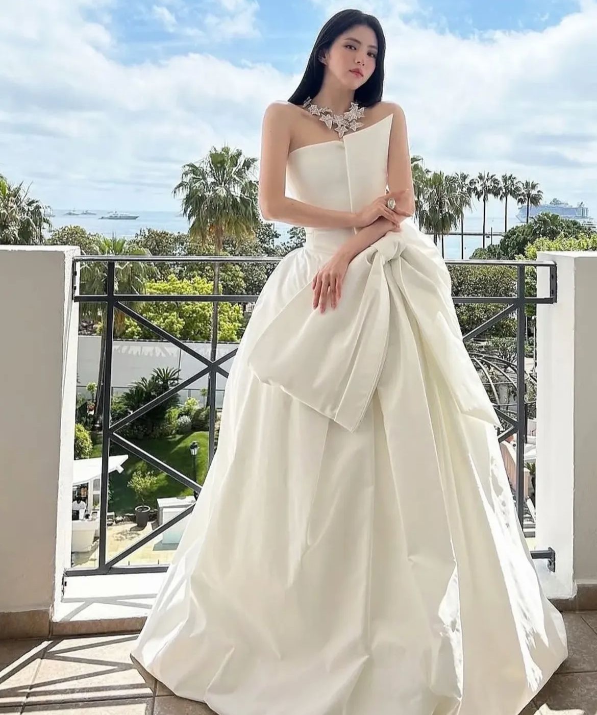 Han So Hee mengenakan gaun berwarna putih susu yang elegan dengan rok yang bervolume, memberikan nuansa klasik dan mewah.