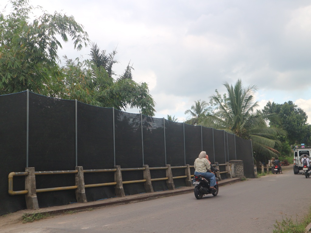 MELINTAS: Seorang pengendara sepeda motor saat melintas di salah satu jembatan yang dipasangkan paranet di Jalan Raya Kali Anyar -Montong Gading, Selasa (20/5).