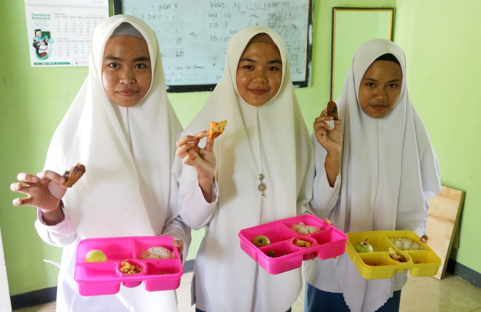 MULAI DISALURKAN: Para santriwati Ponpes Manbaul Ulum menunjukkan menu makanan bergizi gratis, Rabu (21/5).