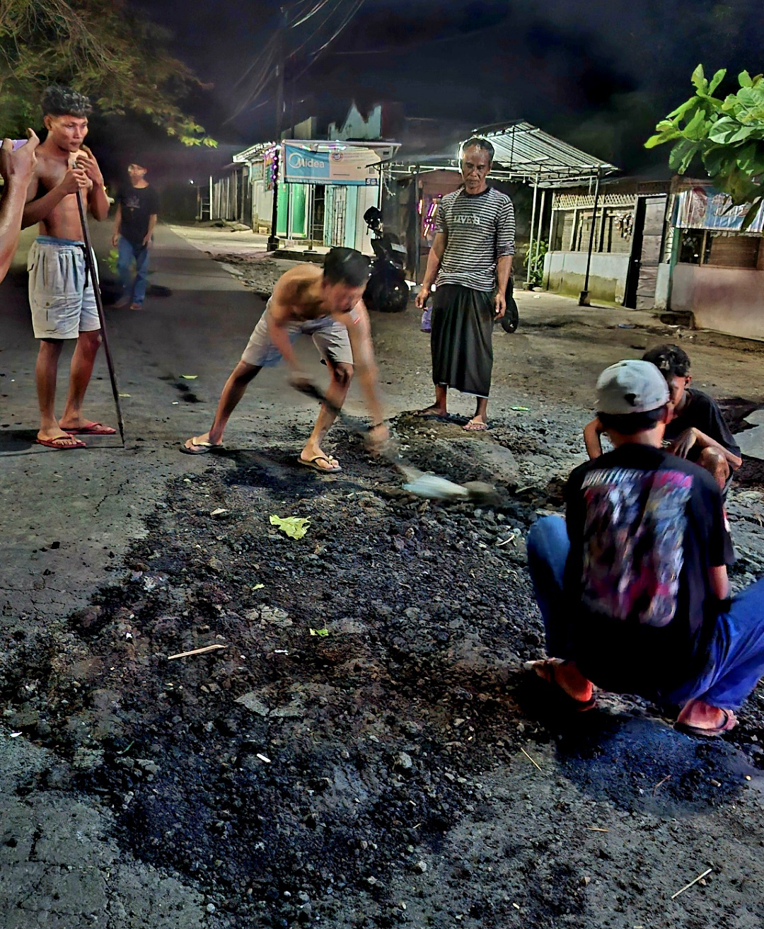 GOTONG ROYONG: Warga bergotong rotong memperbaiki Jalan Raya Praya-Mujur, Lombok Tengah, yang rusak berat, Rabu malam (21/5).