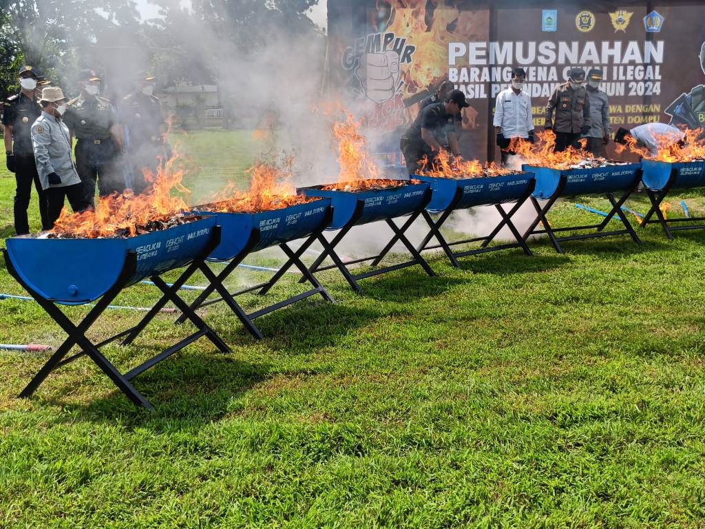 PEMUSNAHAN: Sejumlah pejabat membakar dan memusnahkan rokok dan minuman illegal.