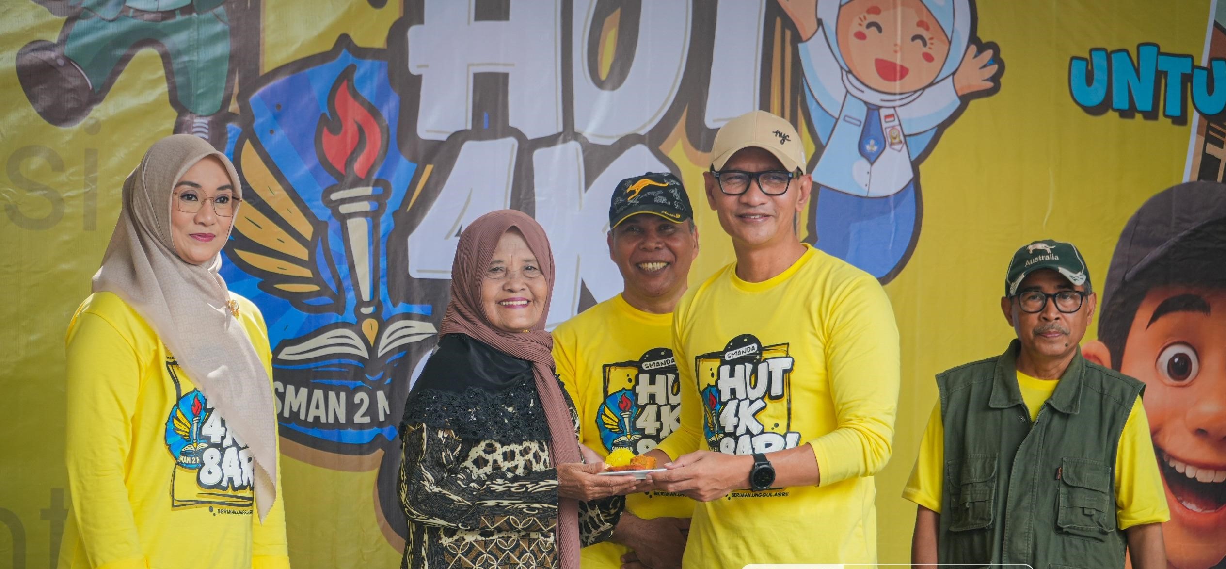 Wali Kota Mataram H Mohan Roliskana didampingi Kepala SMAN 2 Mataram Abdul Kadir Alaydrus memberikan tumpeng kepada guru yang purna tugas pada HUT SMAN 2 Mataram ke-48 dan reuni akbar