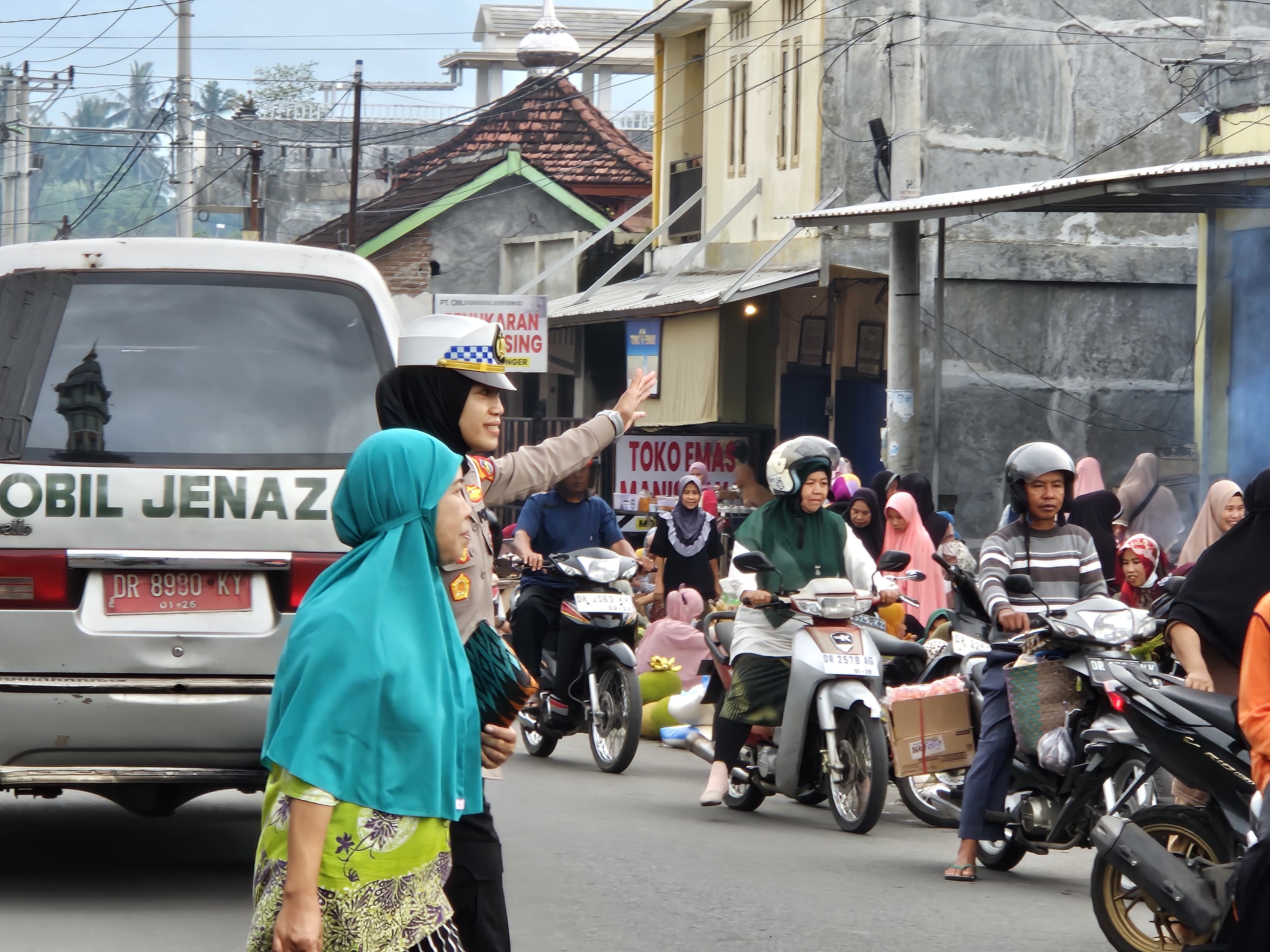 Kasat Lantas Polres Lombok Timur AKP Tira Karista saat membantu ibu-ibu menyebarang di salah satu jalan yang padat kendaraan, Selasa (27/5). (Satlantas Polres Lotim untuk Lombok Post)
