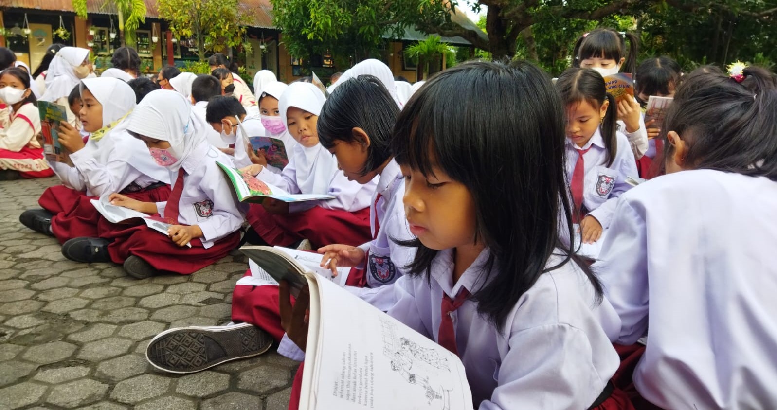 Murid SDN 41 Mataram membaca buku pada program literasi di halaman sekolah setempat.