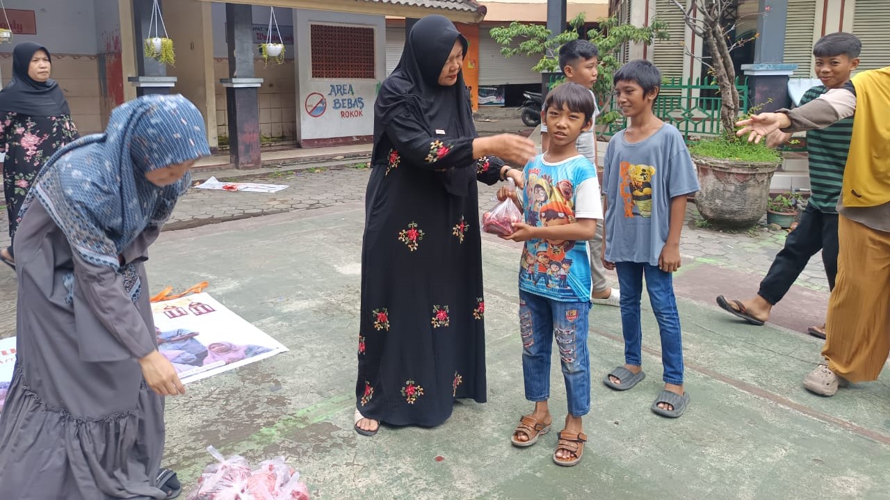 Guru SDN 1 Ampenan menyalurkan daging kurban kepada murid  di sekolah setempat.
