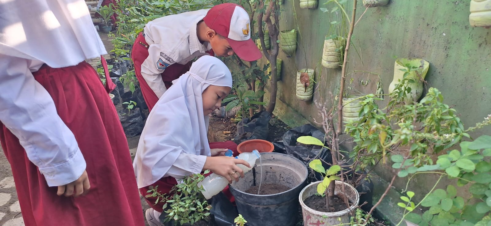 Murid SDN 19 Cakranegara menyiram tanaman di halaman sekolah setempat.