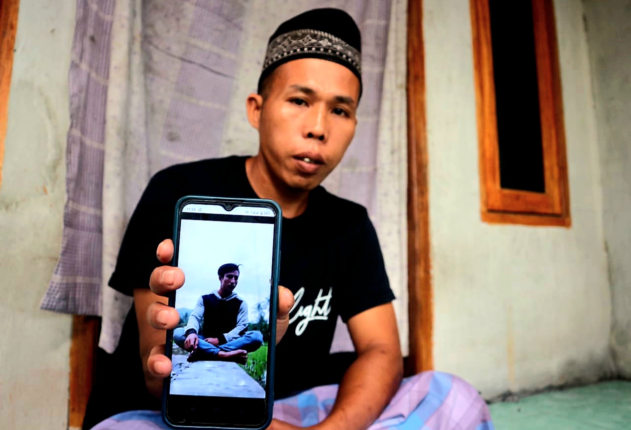 Zukandi, kakak dari Sahri Ramadan, PMI asal Dusun Batu Asak, Desa Buwun Sejati, Kecamatan Narmada Lombok Barat menunjukkan foto adiknya yang dilaporkan meninggal dunia dibunuh rekan sesama PMI.