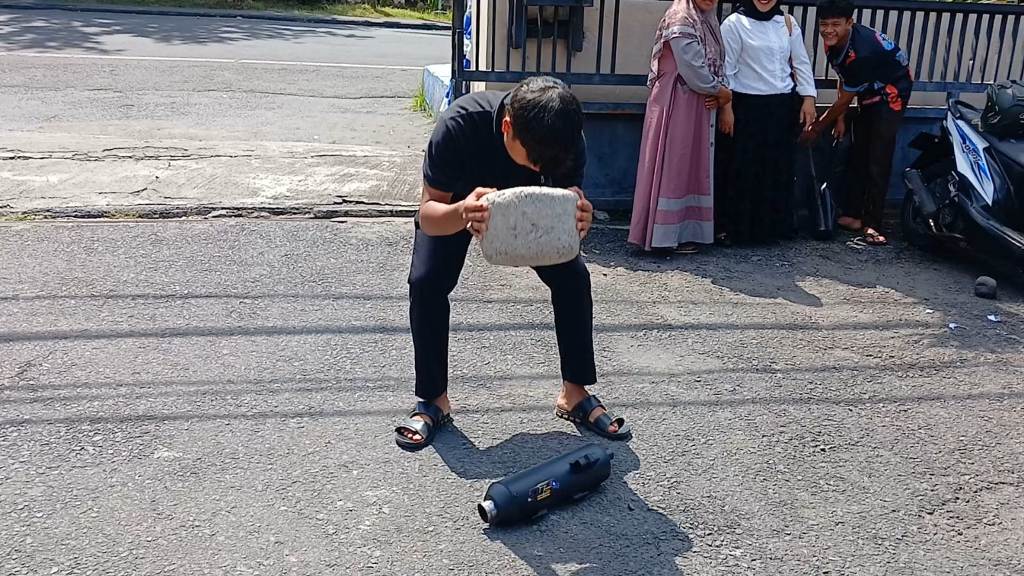 RUSAK: Seorang pelajaran yang terjaring penertiban knalpot brong, saat menghancurkan knalpot miliknya di halaman Satlantas Polres Lotim, Selasa (10/6).