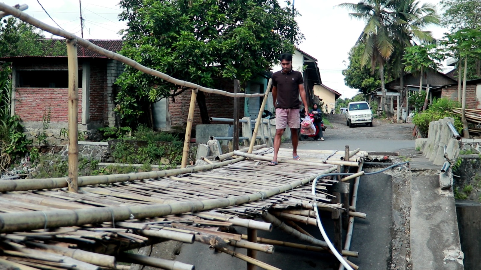 BELUM DIPERBAIKI: Seorang warga melintas di atas jembatan bambu di Desa Mujur, Kecamatan Praya Timur, Lombok Tengah, Rabu (11/6). Jembatan putus akibat bencana ini akan diperbaiki tahun depan.