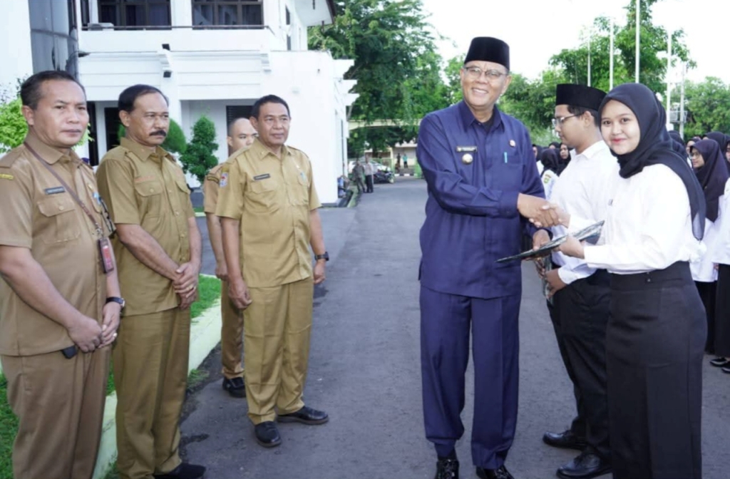 PENYERAHAN SK: Bupati Sumbawa Syarafuddin Jarot menyerahkan SK kepada salah seorang ASN usai upacara di halaman kantor bupati setempat, Senin (16/6).