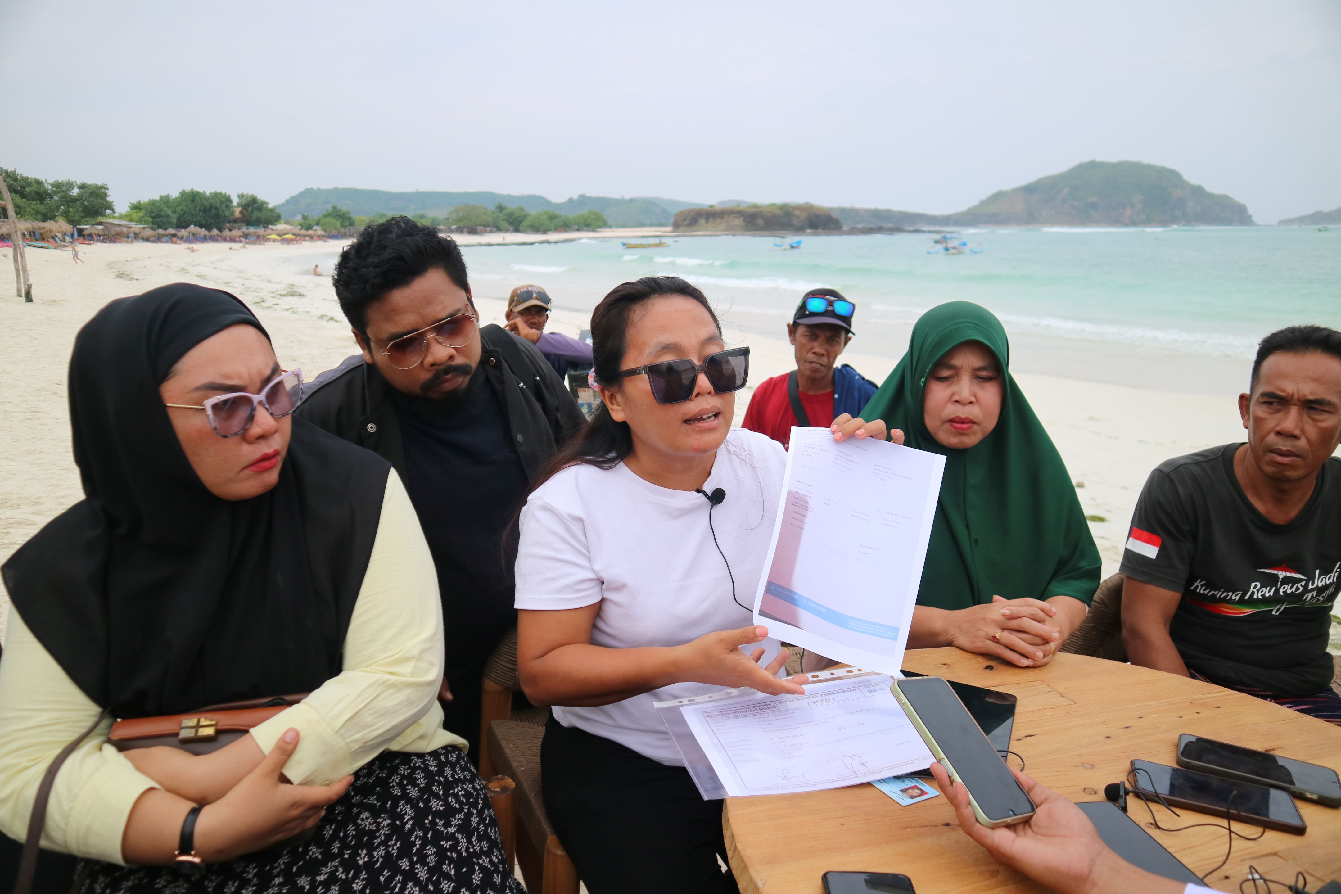 perwakilan warung lokal tunjukkan bukti pembayaran pajak selama berusaha di pesisir Pantai Tanjung Aan, Lombok Tengah