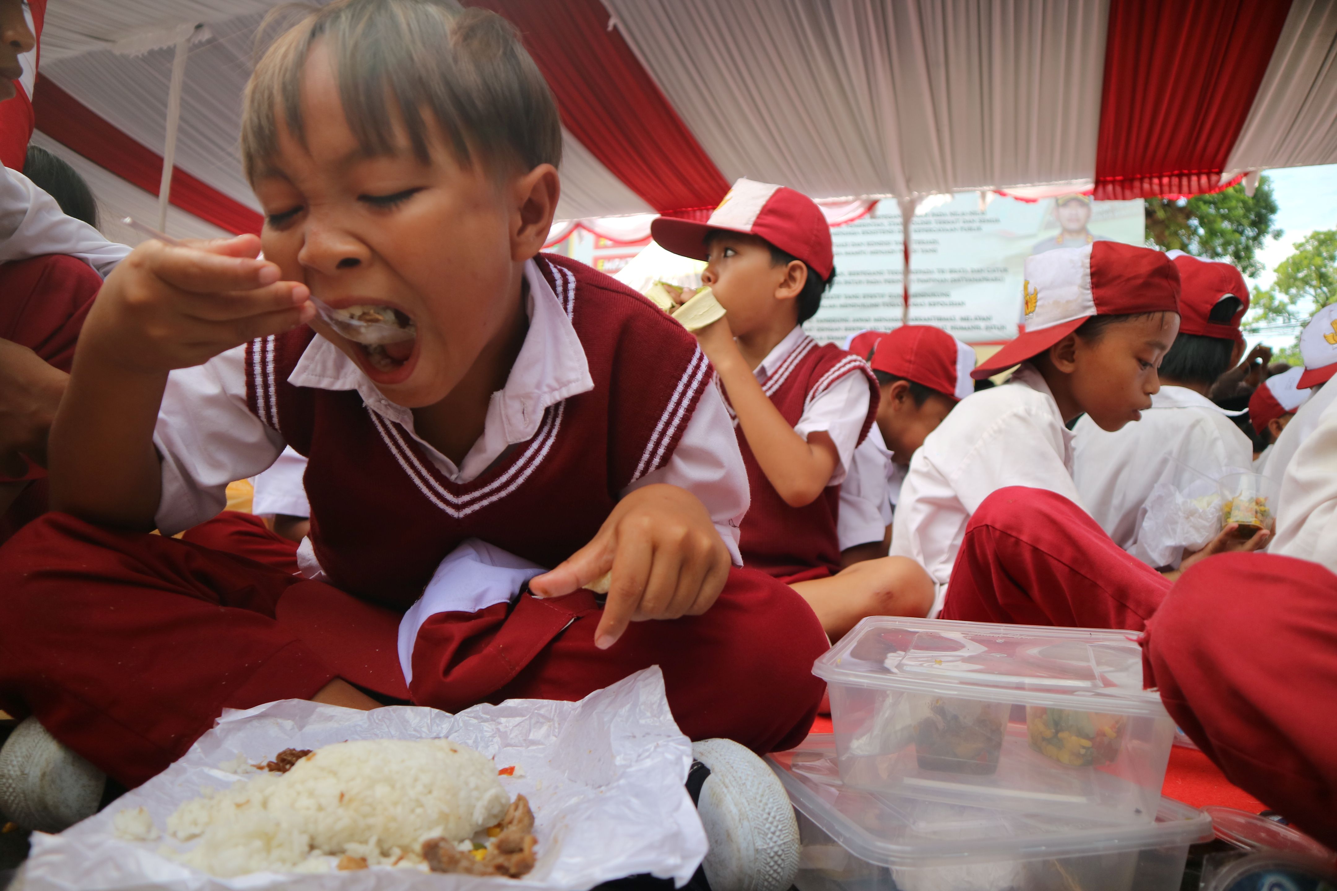 Seorang murid sekolah dasar melahap santapan paket MBG yang dibagikan jajaran Polda NTB dan Polres Loteng, Selasa (24/6).