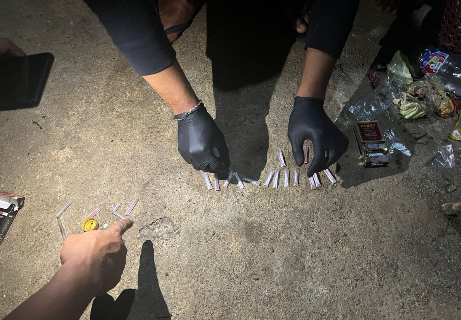 Polisi memperlihatkan barang bukti yang disembunyikan LAS di tempat sampah di rumahnya Desa Kandidi, Dompu, Rabu (2/7).