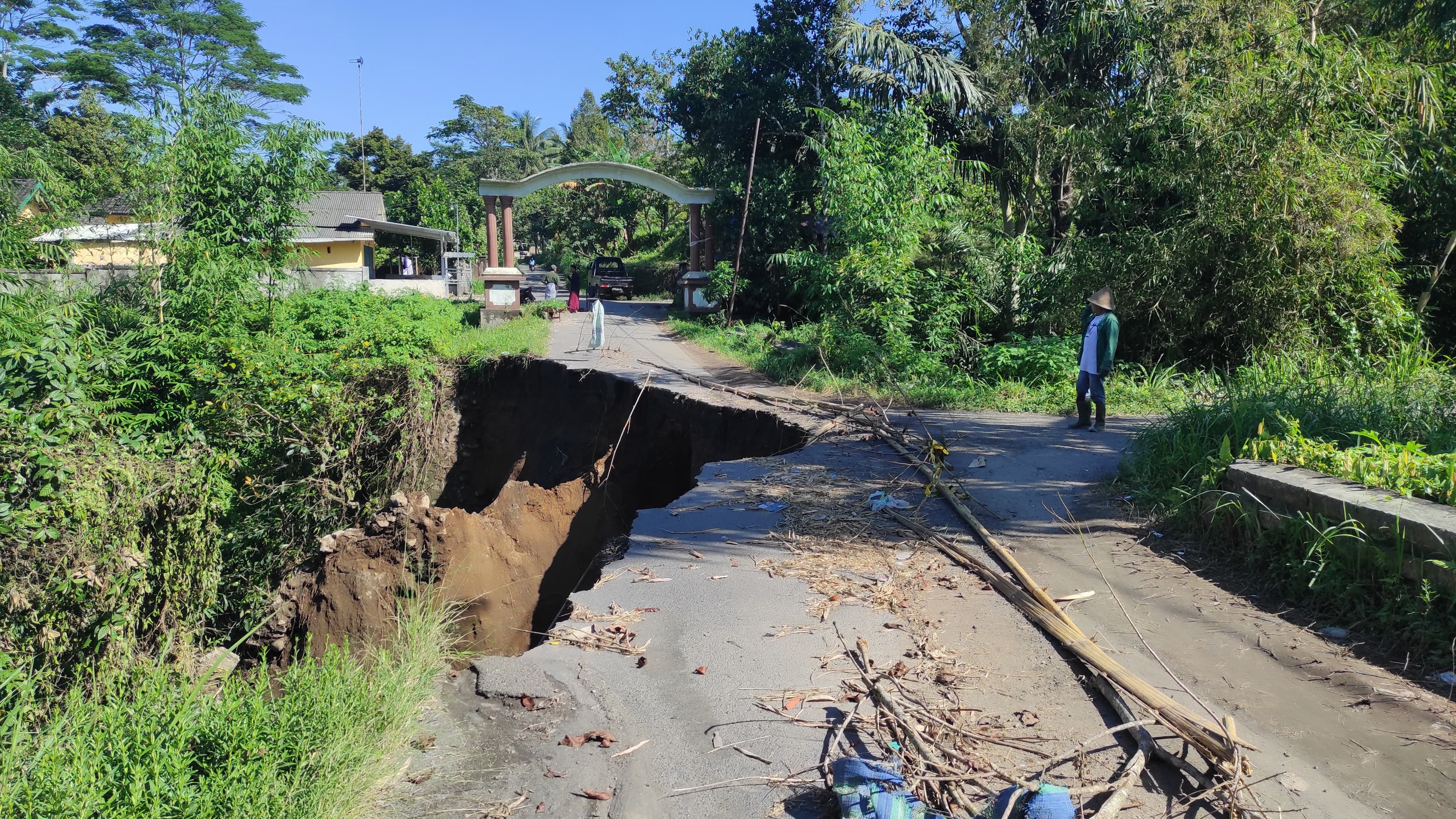 TAK KUNJUNG DIPERBAIKI: Seorang warga melintas jalan di atas jembatan amblas akibat longsor di Dusun Bare Eleh, Desa Aik Bual, Kecamatan Kopang, Loteng, Jumat (4/7).